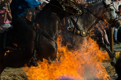 Low section of man jumping horse over fire during equestrian event