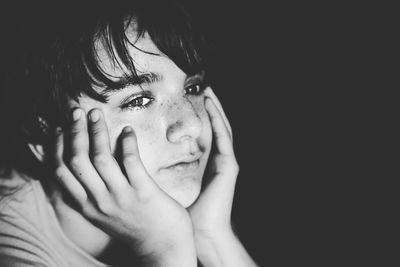 Portrait of young woman against black background