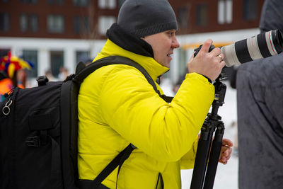 Reportage photographer with camera at outdoor street event in winter