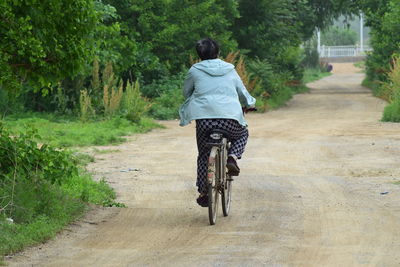 Rear view of man riding bicycle on road