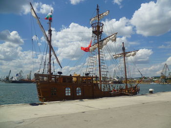 Sailboats moored at harbor against sky