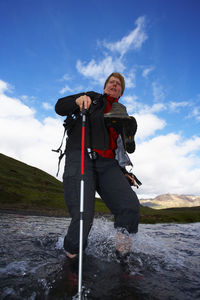 Mature woman crossing river on the laugavegur hiking trail