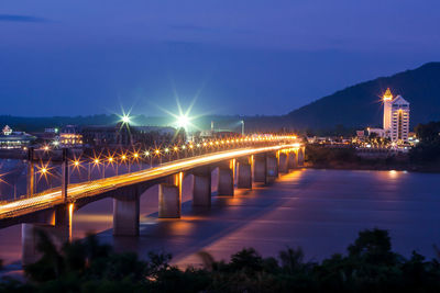 Illuminated bridge over river at night