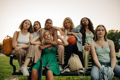 Portrait of multiracial teenage girls sitting together on bench