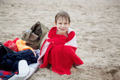 Portrait of happy boy textile crouching at sandy beach