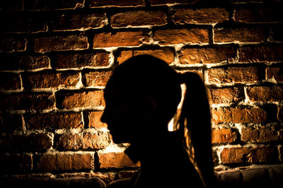 Silhouette woman standing against brick wall