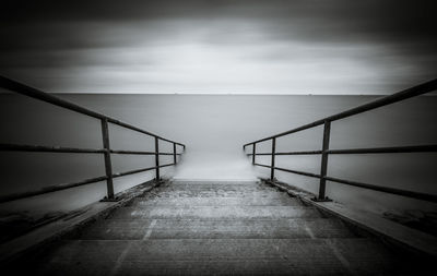 Black and white image of a stairs reaching into the ocean