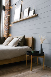 A modern white ceramic vase with dried grass and a cup of coffee or tea beside the double bed.