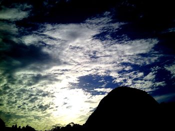 Low angle view of silhouette trees against cloudy sky