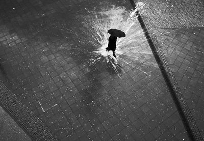 High angle view of person walking on splashed water on footpath in rainy season
