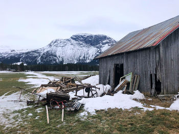 House on field by snowcapped mountain against sky