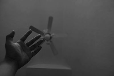 Cropped hand against ceiling fan at home