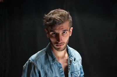 Portrait of young man against black background