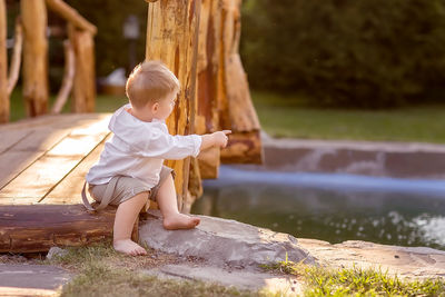 Full length of cute boy sitting on wood