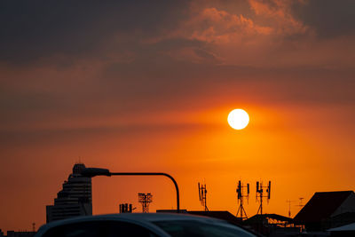 Silhouette car against orange sky during sunset