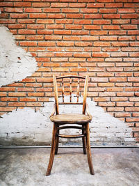 Empty chair against brick wall