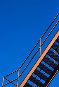 Low angle view of railing against clear blue sky