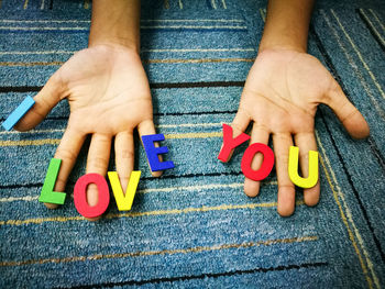 Cropped hands with i love you message on rug