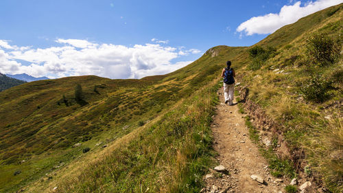 Rear view of man walking on mountain against sky