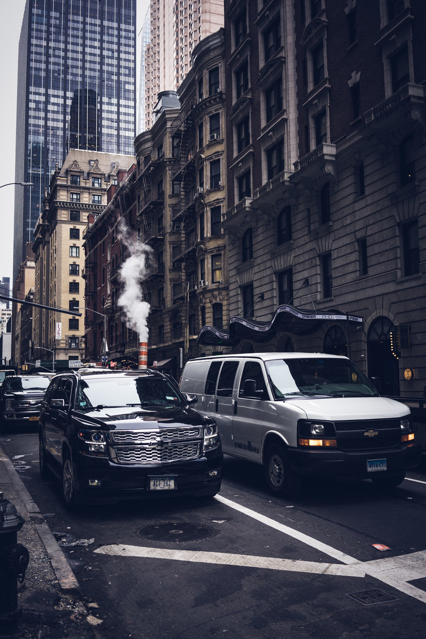 CARS ON CITY STREET AMIDST BUILDINGS