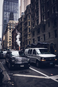 Cars on city street by buildings