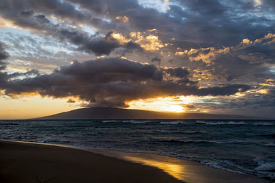 Scenic view of sea against dramatic sky during sunset