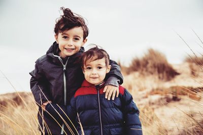 Portrait of siblings standing on field