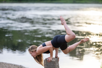 Rear view of woman exercising on lake