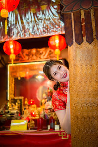 Portrait of smiling woman standing against illuminated decoration