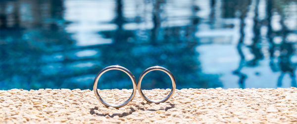 Close-up of wedding rings against swimming pool