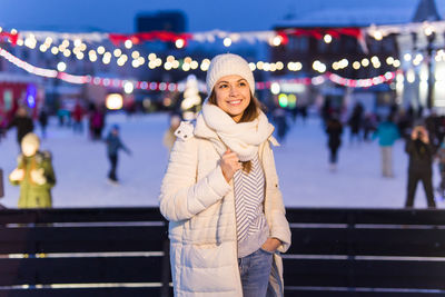 Portrait of young woman standing in city at night