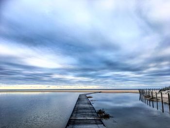 Boardwalk against cloudy sky