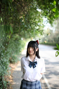 Young woman standing against tree