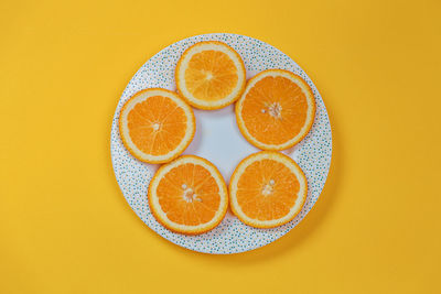 Directly above shot of orange slices against yellow background