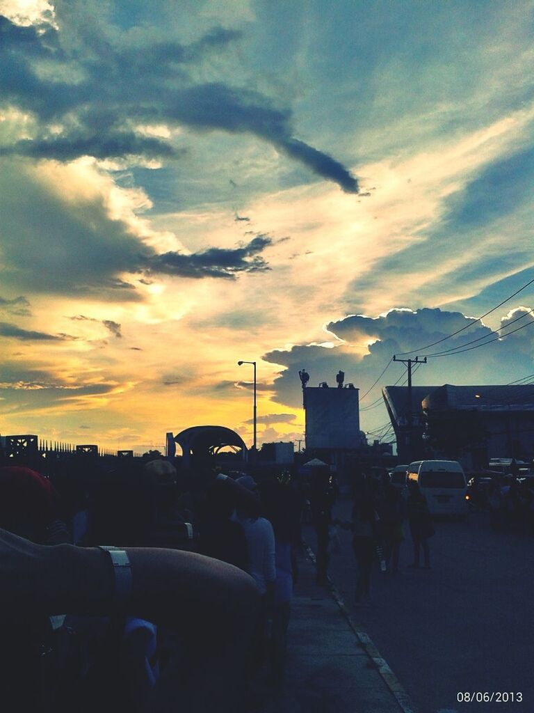 sunset, sky, transportation, cloud - sky, car, mode of transport, silhouette, land vehicle, street, large group of people, cloud, road, building exterior, street light, built structure, city, architecture, travel, men