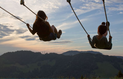 Low angle view of man swinging against mountain