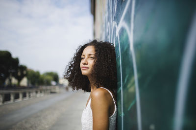 Portrait of young woman leaning against wall
