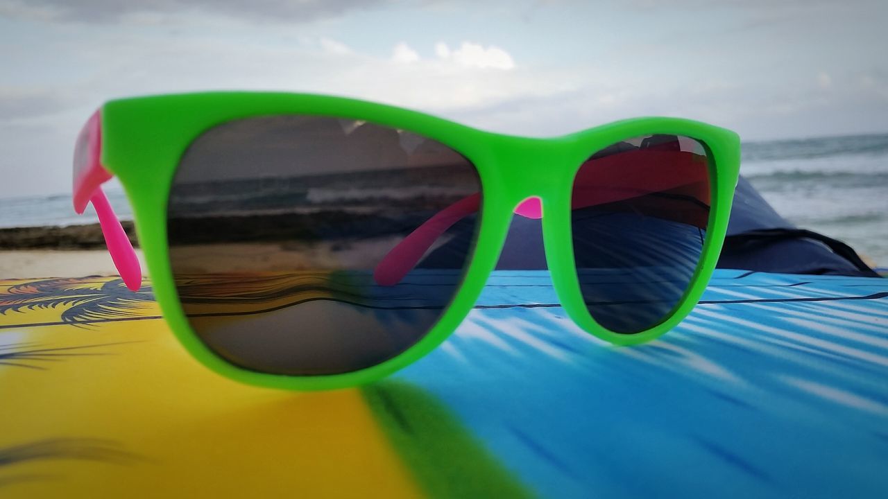 reflection, transportation, close-up, sunglasses, land vehicle, mode of transport, focus on foreground, car, sky, day, part of, outdoors, multi colored, stationary, selective focus, side-view mirror, no people, blue, protection, yellow