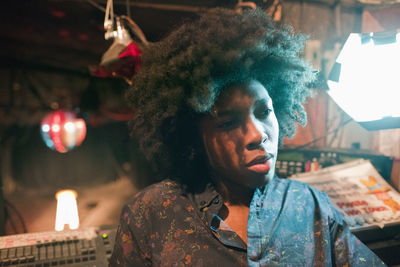 Portrait of young man looking at illuminated shop