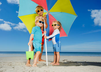 Rear view of woman holding umbrella at beach