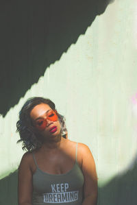 Portrait of a beautiful young woman standing against wall