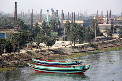 Boats moored on river by buildings in city