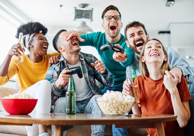 Cheerful friends sitting together by table at home