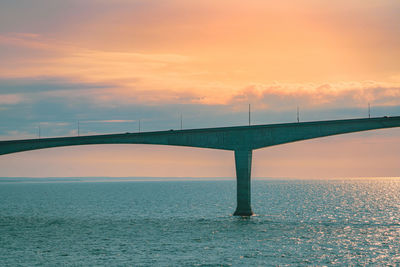 Bridge over sea against sky during sunset