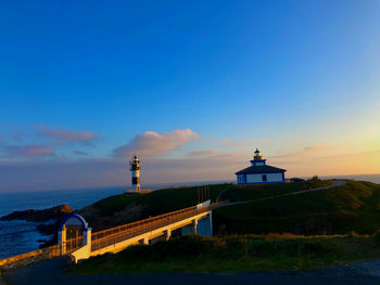 Lighthouse by sea against sky during sunset