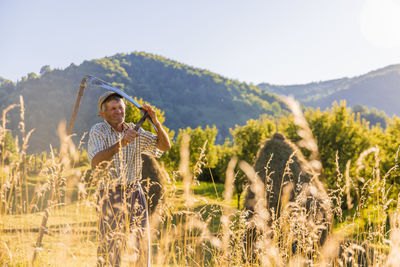 Man standing by plants on field against sky