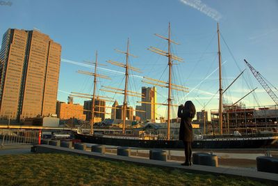 Woman standing by ship in city against clear sky