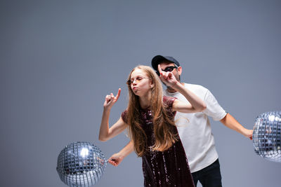 A dynamic dance duo performing with colorful disco balls in a vibrant studio space