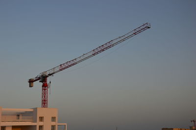 Low angle view of crane against clear sky