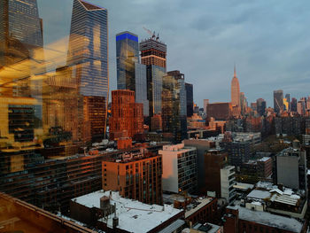Hudson yards and empire state building in nyc during evening, with reflection of sunset lights.